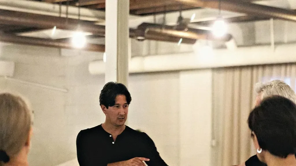 A Beach Ballroom instructor in black walking students through a step during a lesson