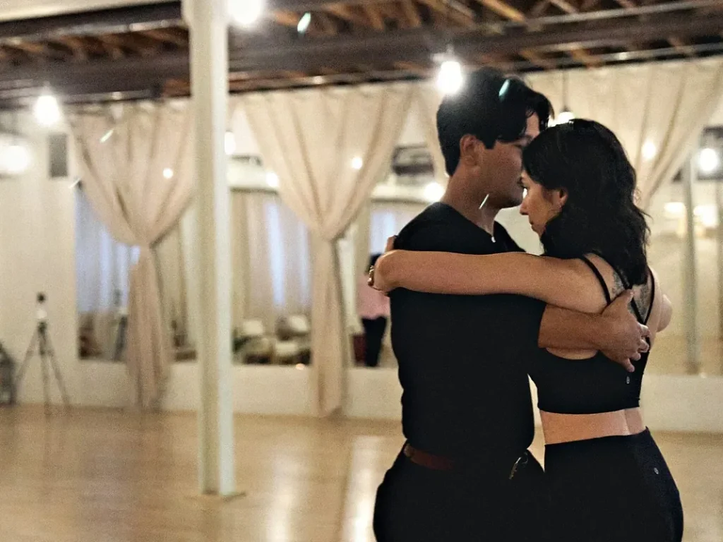 A couple in close hold on the wooden floor at a Beach Ballroom Latin social